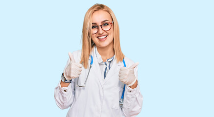 Beautiful caucasian woman wearing doctor uniform and stethoscope success sign doing positive gesture with hand, thumbs up smiling and happy. cheerful expression and winner gesture.