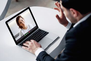 a dark-haired man of European appearance in a black business suit. he sits in a modern office and communicates on a social network on a laptop. my favorite job is senior economist at a bank.