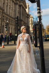 Obraz premium bride in ivory wedding dress stands by traffic lights, background buildings, street