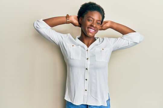 Young african american girl wearing casual clothes relaxing and stretching, arms and hands behind head and neck smiling happy