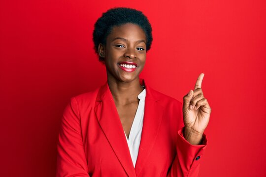 Young african american girl wearing business clothes with a big smile on face, pointing with hand and finger to the side looking at the camera.