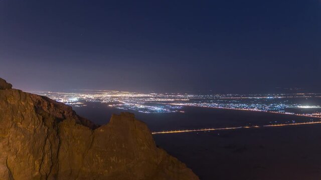 Day to night transition timelapse with rocks and road traffic on Jebel Hafeet. Mountain located primarily in the environs of Al Ain and offers an impressive view over the city. Aerial view from top