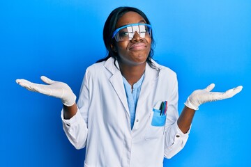Young african american woman wearing scientist uniform clueless and confused with open arms, no...