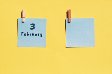 3st of February. 3st day of the month, calendar date. Two blue sheets for writing on a yellow background. Top view, copy space. Winter month, day of the year concept