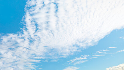 Blue sky and white clouds background - Pillowy clouds cover a blue sky in the background