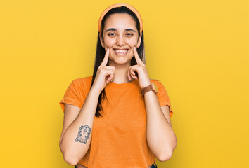 Young hispanic woman wearing casual clothes smiling with open mouth, fingers pointing and forcing cheerful smile