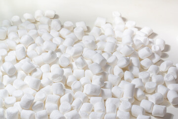 Fototapeta na wymiar Sweet marshmallow marshmallows are scattered on the white table
