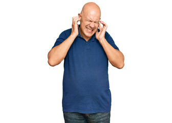 Fototapeta premium Middle age bald man wearing casual clothes covering ears with fingers with annoyed expression for the noise of loud music. deaf concept.