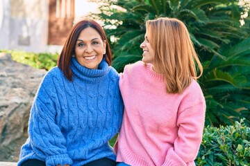 Fototapeta premium Hispanic mother and daughter smiling happy and hugging at the park.