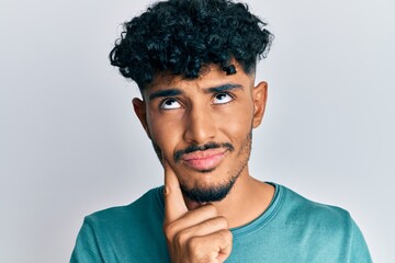 Fototapeta na wymiar Young arab handsome man wearing casual clothes serious face thinking about question with hand on chin, thoughtful about confusing idea