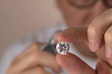 Jeweller asian man looking at diamond through magnifying glass. Diamond dealer evaluating and grading big size gem stone. High quality photo