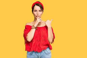 Young brunette woman with short hair wearing casual summer clothes and diadem asking to be quiet with finger on lips pointing with hand to the side. silence and secret concept.