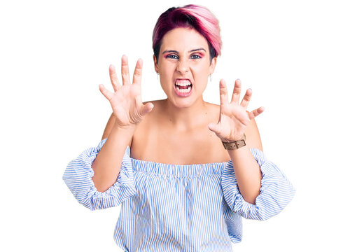 Young beautiful woman with pink hair wearing casual clothes smiling funny doing claw gesture as cat, aggressive and sexy expression