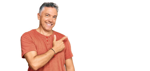 Handsome middle age man wearing casual clothes cheerful with a smile of face pointing with hand and finger up to the side with happy and natural expression on face