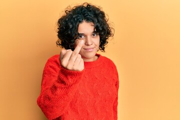 Young hispanic woman with curly hair wearing casual winter sweater showing middle finger, impolite...