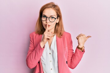 Young caucasian woman wearing business style and glasses asking to be quiet with finger on lips...
