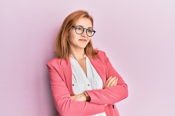 Young caucasian woman wearing business style and glasses looking to the side with arms crossed convinced and confident