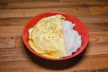 Rice omelette on red plate. Rice omelette in red plate and put on a wooden table.
