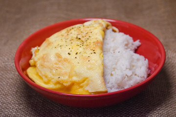 Rice omelette on red plate. Rice omelette in red plate and put on a wooden table.