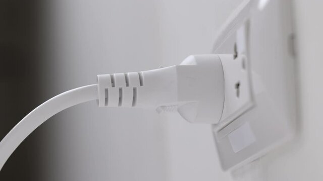 Hand holding Electric plug put on multiple socket. Electrical equipment, electrical wires and power strips in the house. Earth Hour saving electrical energy.