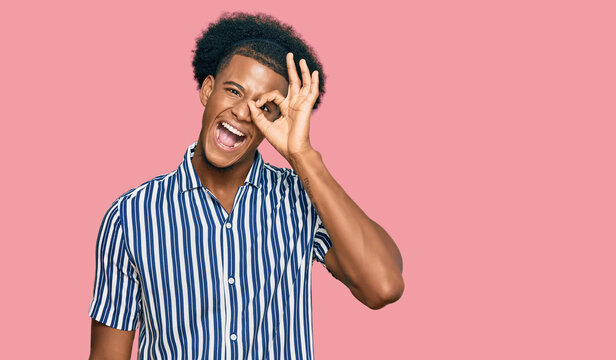 African american man with afro hair wearing casual clothes smiling happy doing ok sign with hand on eye looking through fingers
