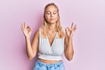 Young blonde girl wearing casual clothes relax and smiling with eyes closed doing meditation gesture with fingers. yoga concept.