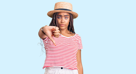 Obraz na płótnie Canvas Young african american woman with braids wearing summer hat looking unhappy and angry showing rejection and negative with thumbs down gesture. bad expression.