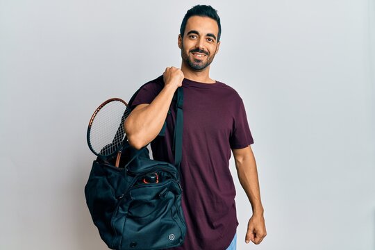 Young Hispanic Man Holding Gym Bag Looking Positive And Happy Standing And Smiling With A Confident Smile Showing Teeth