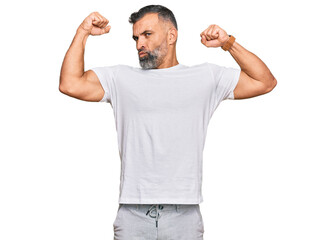 Fototapeta premium Middle age handsome man wearing casual white tshirt showing arms muscles smiling proud. fitness concept.
