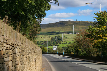 Mossley, England - A view of the rolling hills beside streetlights and an ancient wall on the outskirts of Mossley, under an idyllic blue sky.  Image has copy space.