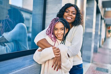 Beautiful african american mother and daughter smiling happy and hugging. Standing with smile on...