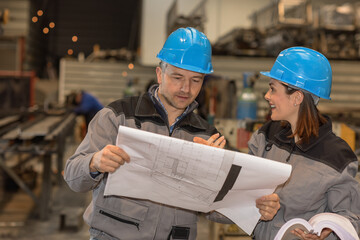 Two workers are having fun in the factory while they are reading