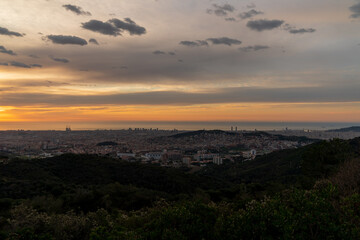 Sunrise on a spring day in the city of Barcelona. We can see the sky, with some clouds that light up like fire, with the sunlight. The water of the Mediterranean Sea, completely flat.