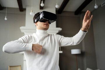 the man put on black virtual reality glasses. learns to be in the digital game. At home, one stands in the living room