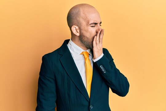 Young hispanic man wearing business suit and tie bored yawning tired covering mouth with hand. restless and sleepiness.