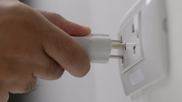 Hand holding Electric plug put on multiple socket. Electrical equipment, electrical wires and power strips in the house. Earth Hour saving electrical energy.