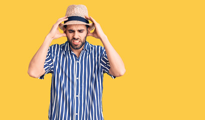 Young handsome man with beard wearing summer hat and striped shirt with hand on head for pain in head because stress. suffering migraine.