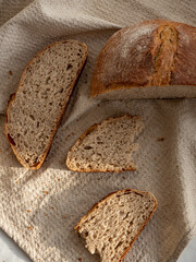 Homemade fresh wheat-rye bread on sourdough on a natural color linen napkin on a white background in the morning light