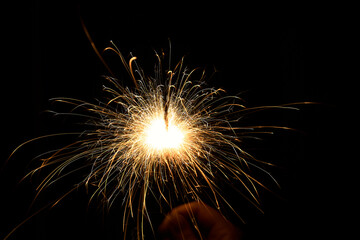 New year sparkler in hands on black background