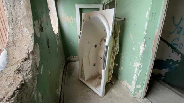 Old used abandoned acrylic bathtub on the staircase flight balcony in multi-story apartment building