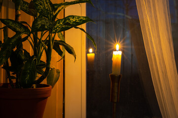 A lonely candle stands by the window in the evening as a token of memory of those who died in wars