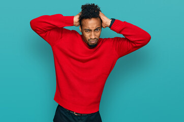 Fototapeta premium Young african american man with beard wearing casual winter sweater crazy and scared with hands on head, afraid and surprised of shock with open mouth
