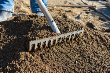 The gardener loosens the ground with a rake