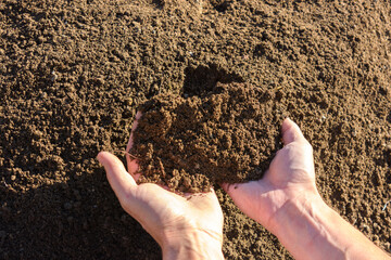 Hands hold fertile soil in the palms, close-up