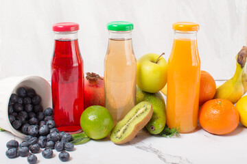 set of fruit juice bottles with fresh fruits on gray table, top view