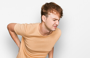 Young caucasian man wearing casual clothes suffering of backache, touching back with hand, muscular pain