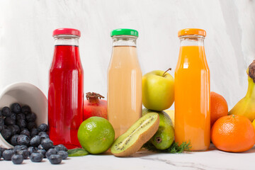 set of fruit juice bottles with fresh fruits on gray table, top view