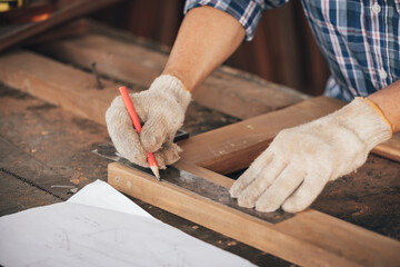 closeup man carpenter measuring wood with ruler in workshop(vintage tone)