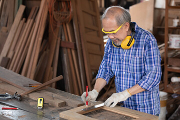 senior man carpenter measuring wood with ruler in workshop