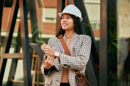 Young asian architect woman smiling happy writing on clipboard at the city.